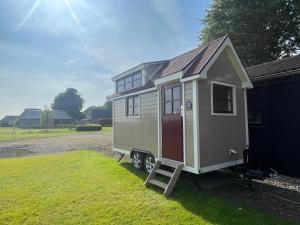 a tiny house on a trailer in a yard at Op zoek naar een leuke overnachting Te huur Prachtig Tiny House De Hutte in Siddeburen