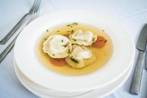 a white plate of dumpling soup on a table at Leśna Ryba I Domki nad jeziorem z parkiem linowym in Jedlanka Stara