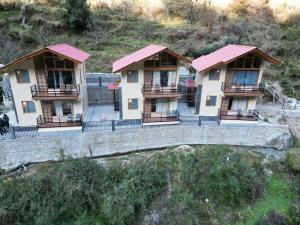two houses with red roofs on a hill at Riverdale Cottage and Cafe Jibhi in Jibhi