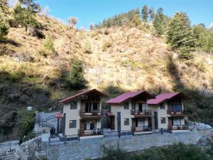 a building with a mountain in the background at Riverdale Cottage and Cafe Jibhi in Jibhi