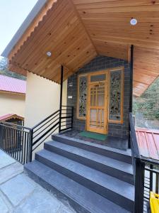 a house with a wooden door and stairs at Riverdale Cottage and Cafe Jibhi in Jibhi