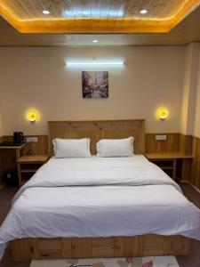 a bedroom with a large bed with white sheets at Riverdale Cottage and Cafe Jibhi in Jibhi