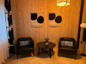 two chairs and a table in front of a wooden wall at Apartament M6 in Leśna