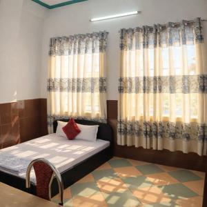 a room with a bed and curtains and a table at Kiến An Hotel Cần Thơ in Can Tho