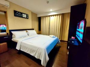 a bedroom with a bed and a flat screen tv at eL ROYALE by Farizi Rooms in Bandung