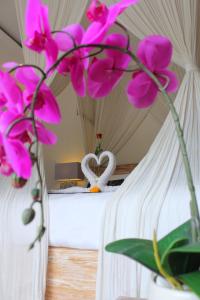 a room with a bed with pink flowers on it at Villa D'Uma in Ubud