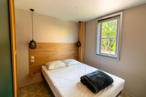a bedroom with a white bed with a window at Camping Les Pins - Bord de mer in Argelès-sur-Mer