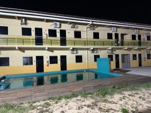 a building with a swimming pool in front of it at pousada ondas do atlântico in Salinópolis