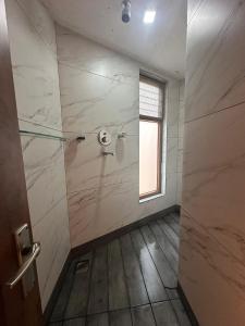 a bathroom with a shower with marble walls and a window at Bagaan Villa Homestay in Ilām