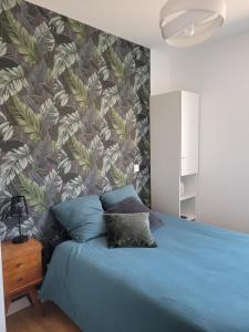 a bedroom with a blue bed with a tropical wallpaper at Les Aigrettes - Appartement spacieux - Terrasse et garage in Concarneau