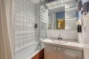 a white tiled bathroom with a sink and a shower at Brit Hotel Florimont in Saint-Ferréol +28 photos