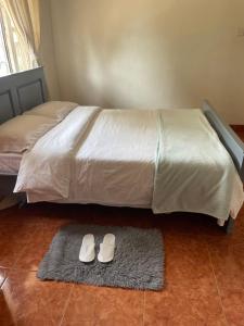 a bed with a pair of white shoes on a rug at Suzie's Nest in Lilongwe