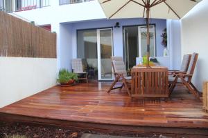 eine Terrasse mit einem Tisch, Stühlen und einem Sonnenschirm in der Unterkunft Garden Apartment in Lissabon