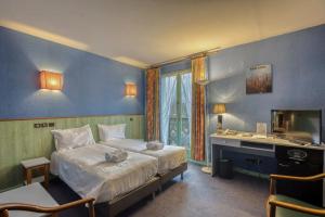 a bedroom with a bed and a desk and a television at Brit Hotel Florimont in Saint-Ferréol