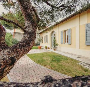 a tree in front of a house with a brick sidewalk at INVENTO bnb unconventional maison in Civitanova Marche