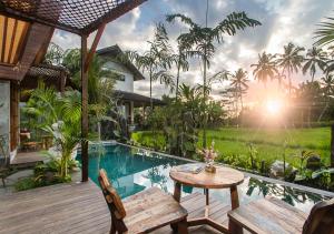 a patio with a table and chairs and a pool at Bara Villa by GenuineHost in Tegalalang