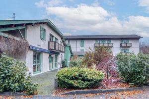 a white house with green windows and bushes at Brit Hotel Florimont in Saint-Ferréol