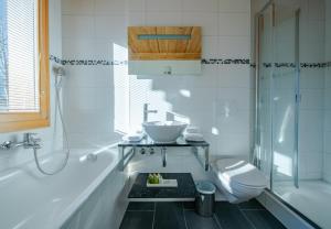 a white bathroom with a sink and a toilet at Chalet Stella Penthouse Residence in Wengen +27 photos