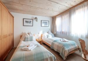 a bedroom with two beds and a window at Chalet Stella Penthouse Residence in Wengen