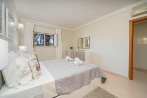 a white bedroom with a bed with white pillows at Vila da Praia by ALgest in Alvor +33 photos