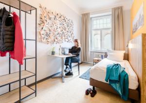 a woman sitting at a desk in a hotel room at Three Little Pigs Hostel - Your Berlin Castle in Berlin +20 photos