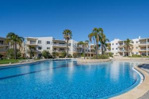 a large swimming pool with palm trees in front of apartment buildings at Vila da Praia by ALgest in Alvor