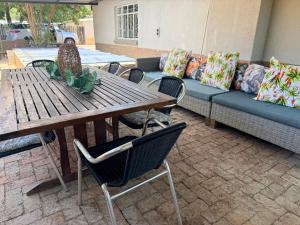 a wooden table with chairs and a couch at Lielies Guesthouse in Parys