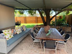 a picnic table with chairs and a couch under a canopy at Lielies Guesthouse in Parys