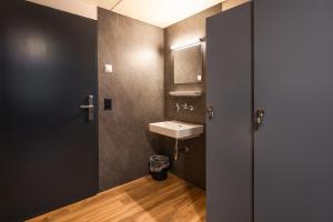 ein Badezimmer mit Waschbecken, Spiegel und Tür in der Unterkunft Eiger Lodge Easy in Grindelwald