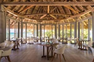 a restaurant with tables and chairs and windows at Canonnier Beachcomber Golf Resort & Spa in Pointe aux Canonniers