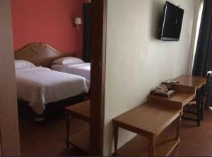 a hotel room with a bed and a table and a mirror at Nina Hotel Syariah in Salatiga