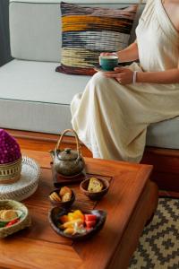 a woman sitting on a couch with a coffee table with food at La Résidence Phou Vao in Luang Prabang +81 photos