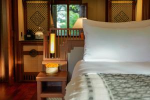 a bedroom with a bed and a lamp on a table at La Résidence Phou Vao in Luang Prabang