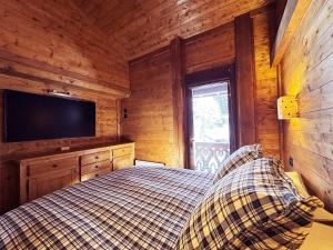 a bedroom with a bed and a flat screen tv at Exceptional Duplex, Cozy & Authentic Atmosphere in Les Gets