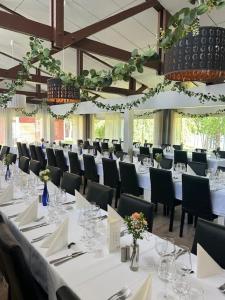 a banquet hall with white tables and black chairs at Hotelli Lepolampi in Espoo