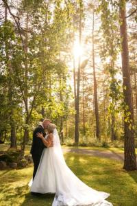 a bride and groom are kissing in a forest at Hotelli Lepolampi in Espoo