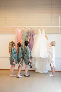 a woman looking at a wedding dress on a rack at Hotelli Lepolampi in Espoo