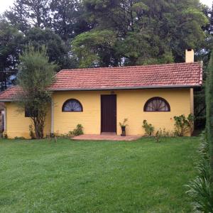 a yellow house with a red roof in a yard at Passarim Chalé in Monte Verde