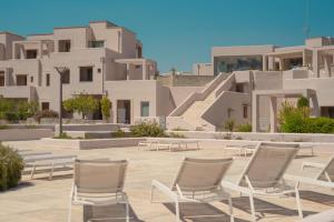 a row of white chairs in front of buildings at Basiliani - CDSHotels in Otranto