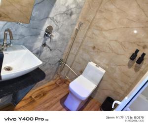 a bathroom with a white toilet and a sink at AmarVandana Palace in Rādha Kund
