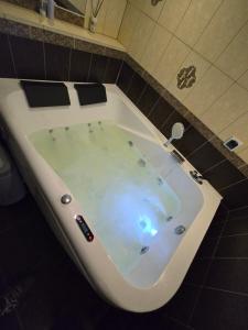 a white bath tub in a tiled bathroom at Old Wine House, self check - in in Klaipėda