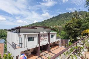 a large white building with a mountain in the background at Pathaya in Ban Kata