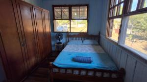 a bedroom with a bed with blue sheets and two windows at Alaercio goulart in Palhoça
