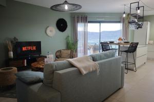a living room with a couch and a kitchen with a table at I Salini - T3 élégant & calme près du centre - Classé 4 étoiles in Porto-Vecchio