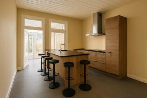a kitchen with a island with bar stools at Groepsverblijf Villa d'Uylenburgh in Hommerts