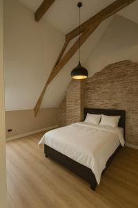 a bedroom with a large bed and a brick wall at Groepsverblijf Villa d'Uylenburgh in Hommerts