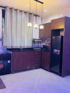 a kitchen with wooden cabinets and a black refrigerator at Luxury homes ug in Kampala