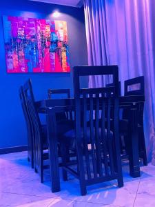 a dining room with black chairs and a painting at Luxury homes ug in Kampala