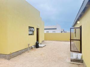 a yellow building with a gate in a courtyard at Pwake Luna Guesthouse in Swakopmund
