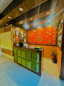 a restaurant with a counter with green and orange at Hotel Royal Orbit By Arony Hospitality Dehradun in Dehradun